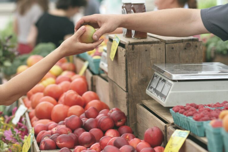 person giving fruit to customer at farmers market